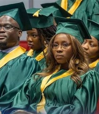 Des diplômés en toge verte et or dans la salle